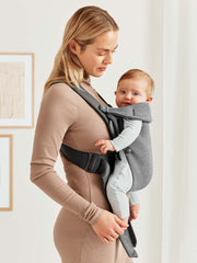 BabyBjörn Mini worn by caregiver demonstrates ergonomic, close contact support.