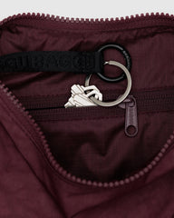 BAGGU crescent bag in mahogany, side view, keeps cards and keys organized with a secure strap.