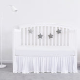 Biloban white crib skirt with pleated design and pompoms for a polished nursery