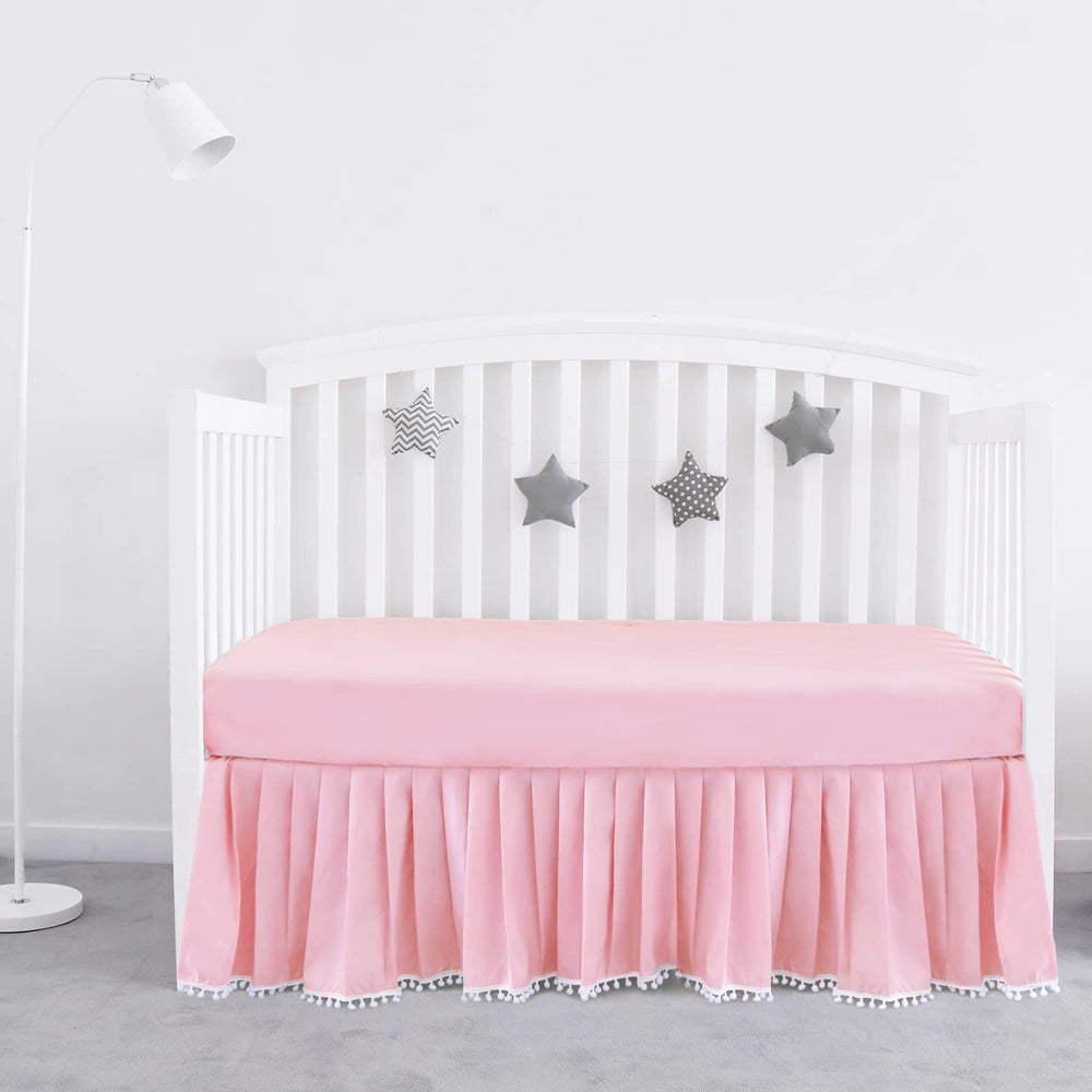 Biloban pink crib skirt pleated with pompoms enhances crib decor and tidy under-bed space