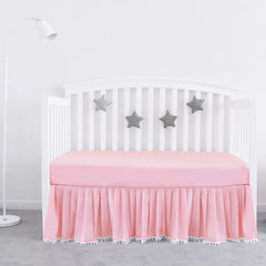 Biloban pink crib skirt pleated with pompoms enhances crib decor and tidy under-bed space