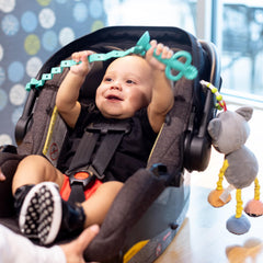 Busy Baby Toy Bungee attached to a stroller for convenient on-the-go play.
