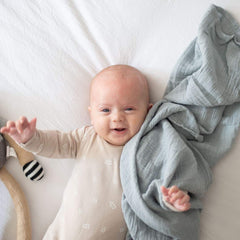 Ely's & Co Misty Blue Dottie swaddle on baby, cozy and secure.