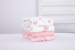 Flexora Muslin Swaddle Blanket Pink Dreams wrapped around a sleeping newborn.