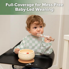 Haakaa smock bib with crumb pocket to catch spills and crumbs.