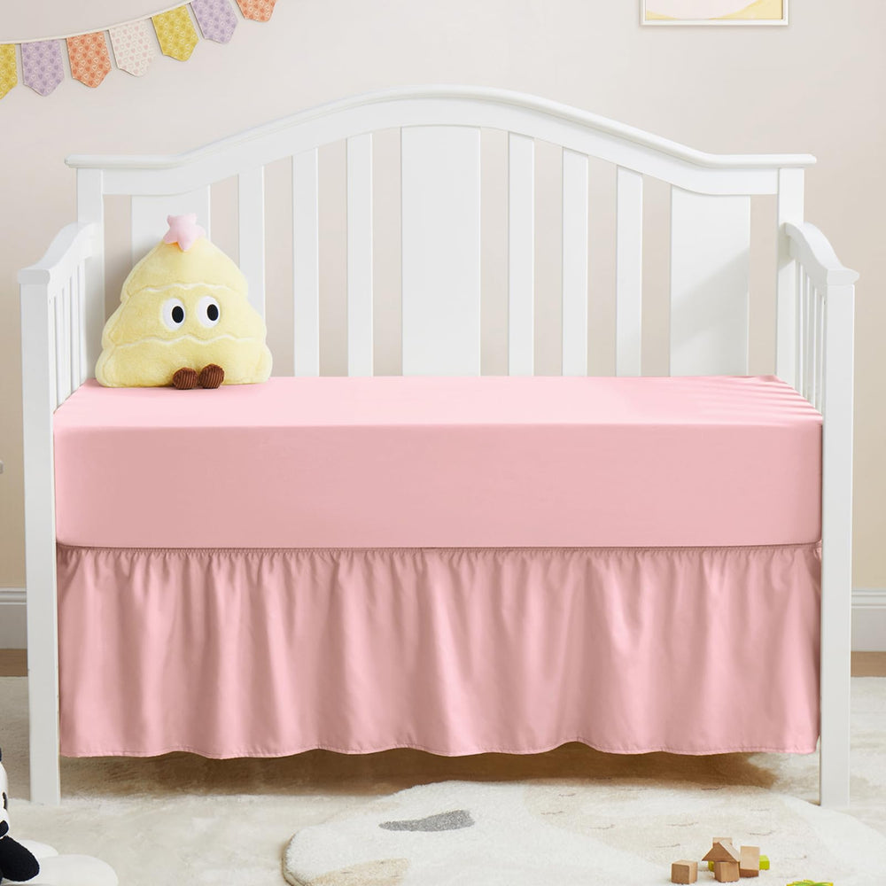 Horbaunal pink crib skirt and sheet set shown together for a coordinated nursery look.