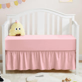 Horbaunal pink crib skirt and sheet set shown together for a coordinated nursery look.