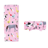 Little Sleepies Lunaluxe swaddle blanket in pink farm animals, buttery-soft fabric for newborn comfort.