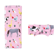 Little Sleepies Lunaluxe swaddle blanket in pink farm animals, buttery-soft fabric for newborn comfort.