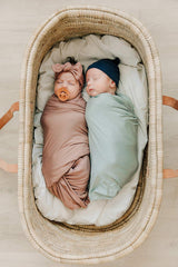 Mebie Baby Sage stretch swaddle shown in nursery coordinates with outfits