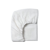 Meracorallo muslin crib sheet in white shows a snug, secure fit for standard cribs.