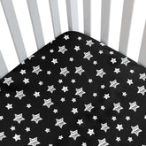 Moonsea Black Star crib sheet side view demonstrates snug fit for a standard crib