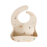 Mushie dinosaur bib with adjustable neck for a snug, comfortable fit during meals.