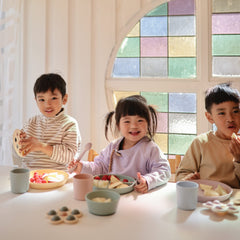 Mushie flatware set powder blue in child hands during meal.
