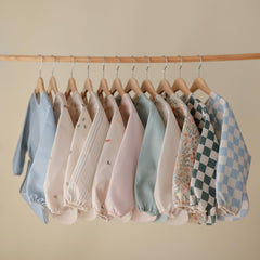 Mushie long sleeve bib side view with pocket catches spills