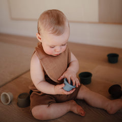 Mushie two-pack muslin bibs in tan and fog meet daily drool needs.