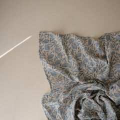 Mushie Muslin Swaddle Blanket blue flowers close-up breathable fabric ideal for airy naps.