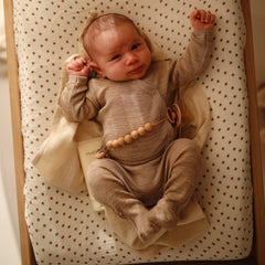 Mushie Rainbows cover on a changer with elastic edge for snug fit.