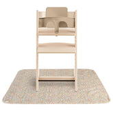 Mushie Splat Mat Pastel Blooms under high chair catching spills for easy cleanup