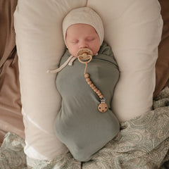 Baby wrapped snugly in Mushie Stretchy Swaddle for secure swaddling.