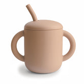 Mushie training cup with spill-proof lid protects surfaces during meals.
