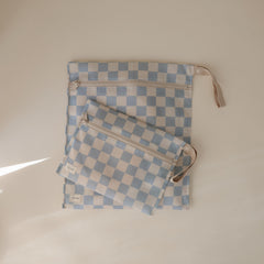 Mushie wet bag blue-check with handle and snap for stroller attachment.