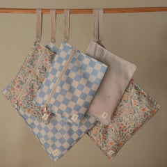 Mushie blue-check wet bag open view with handle for stroller attachment.