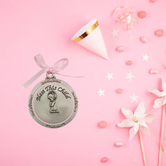 McVan round crib medal close-up highlights delicate pink ribbon detail