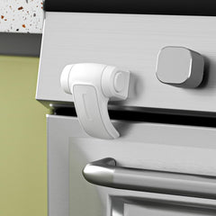 SAFELON oven lock shown with adhesive installation securing the oven door.