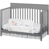 Salcod universal swing-down crib rail guard in white shown on a standard crib barrier
