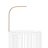 Stokke Sleepi Drape Rod Natural mounted on crib for soft nursery drapery.