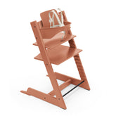 Stokke Tripp Trapp Terracotta with Baby Set attached for ages 6-36 months at the family table.