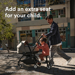 Child sits or stands on the Stokke YOYO Board during a city stroll.