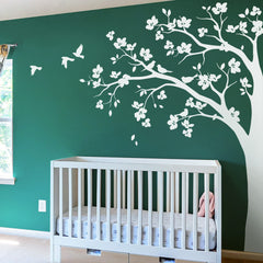 Studio Quee large corner tree wall decal with big blossoms and birds adds cozy, whimsical touch to nurseries.