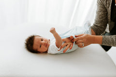 Infant wearing Swaddelini with arms-out, transitioning to wearable blanket mode.