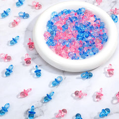 XLIUAX 100-pack mini acrylic pacifiers in blue and pink for colorful baby shower decor and gender reveal ideas.