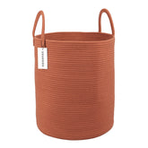 XUANGUO rust-red cotton rope laundry basket viewed in a living room corner for tidy clothes storage.