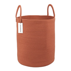 XUANGUO rust-red cotton rope laundry basket viewed in a living room corner for tidy clothes storage.