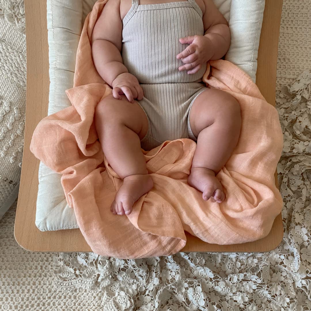 Baby with nursing cover using aden + anais swaddle blanket for privacy.