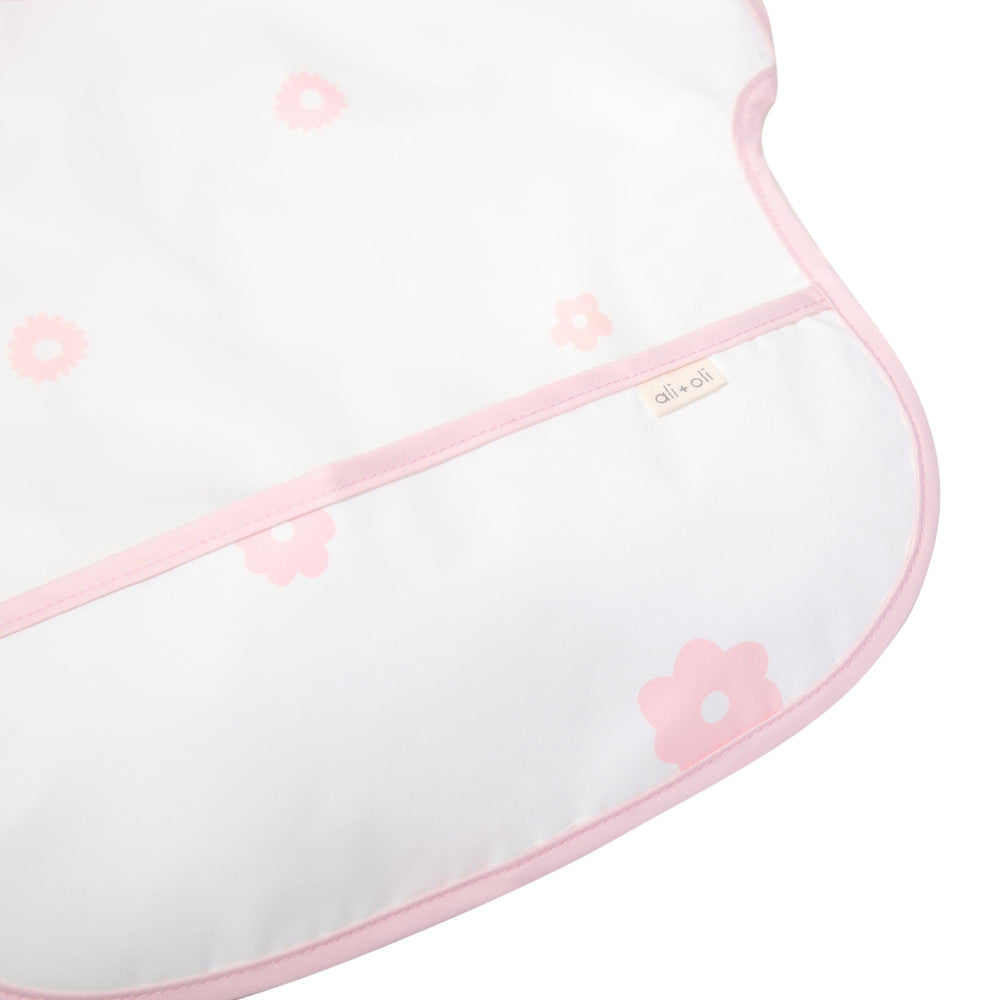 Ali+Oli pink flowers smock bib worn by a baby at mealtime