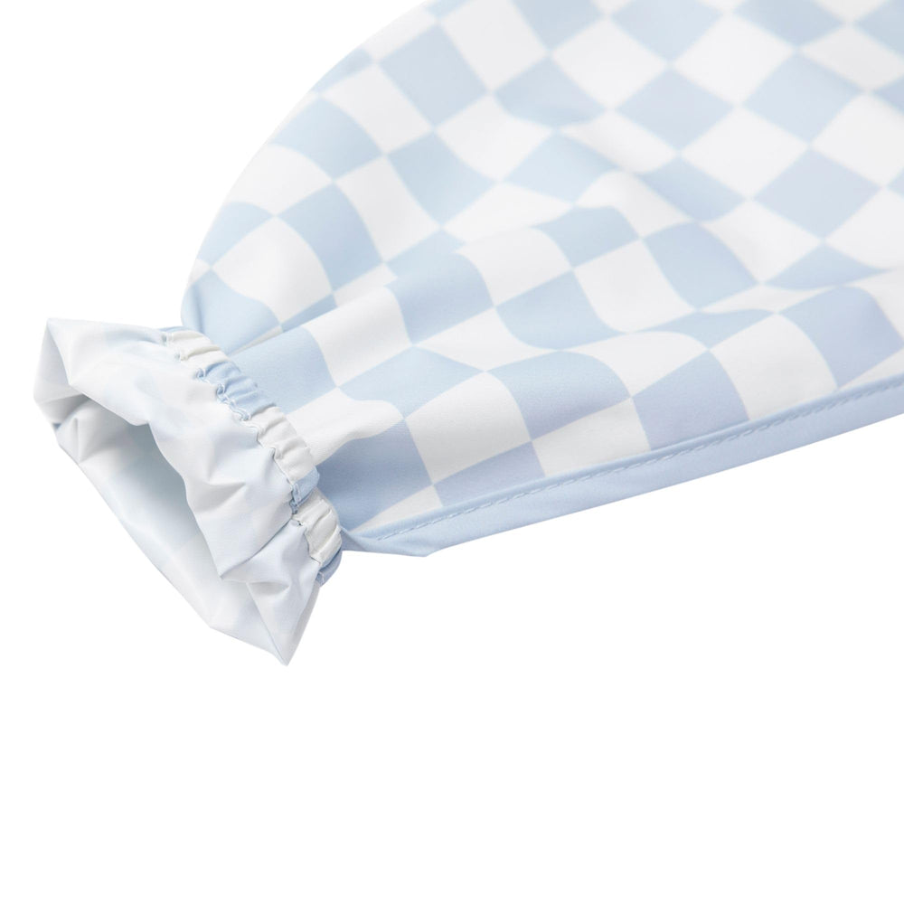 Ali+Oli blue checkers smock bib folded for travel in a diaper bag.