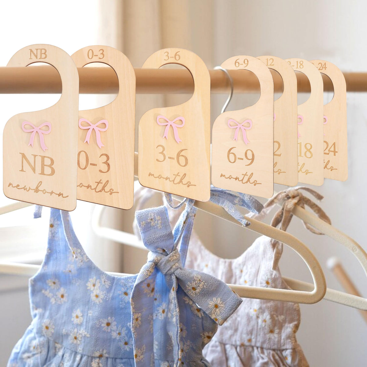 AOQURE wooden bow closet divider on a nursery rod helps keep outfits organized.