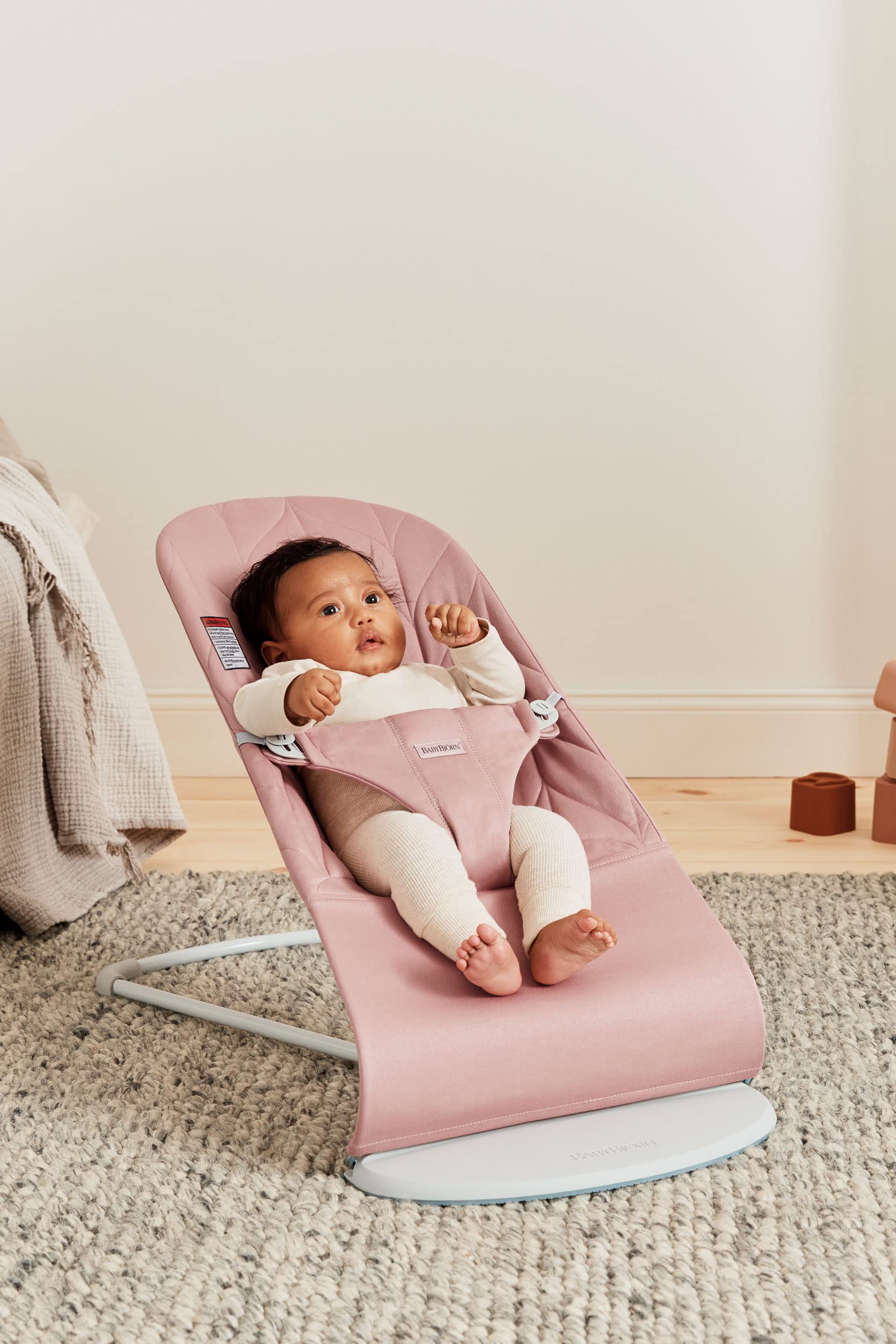 BabyBjörn Bouncer Bliss with petal quilt texture in dusty pink; cozy surface.