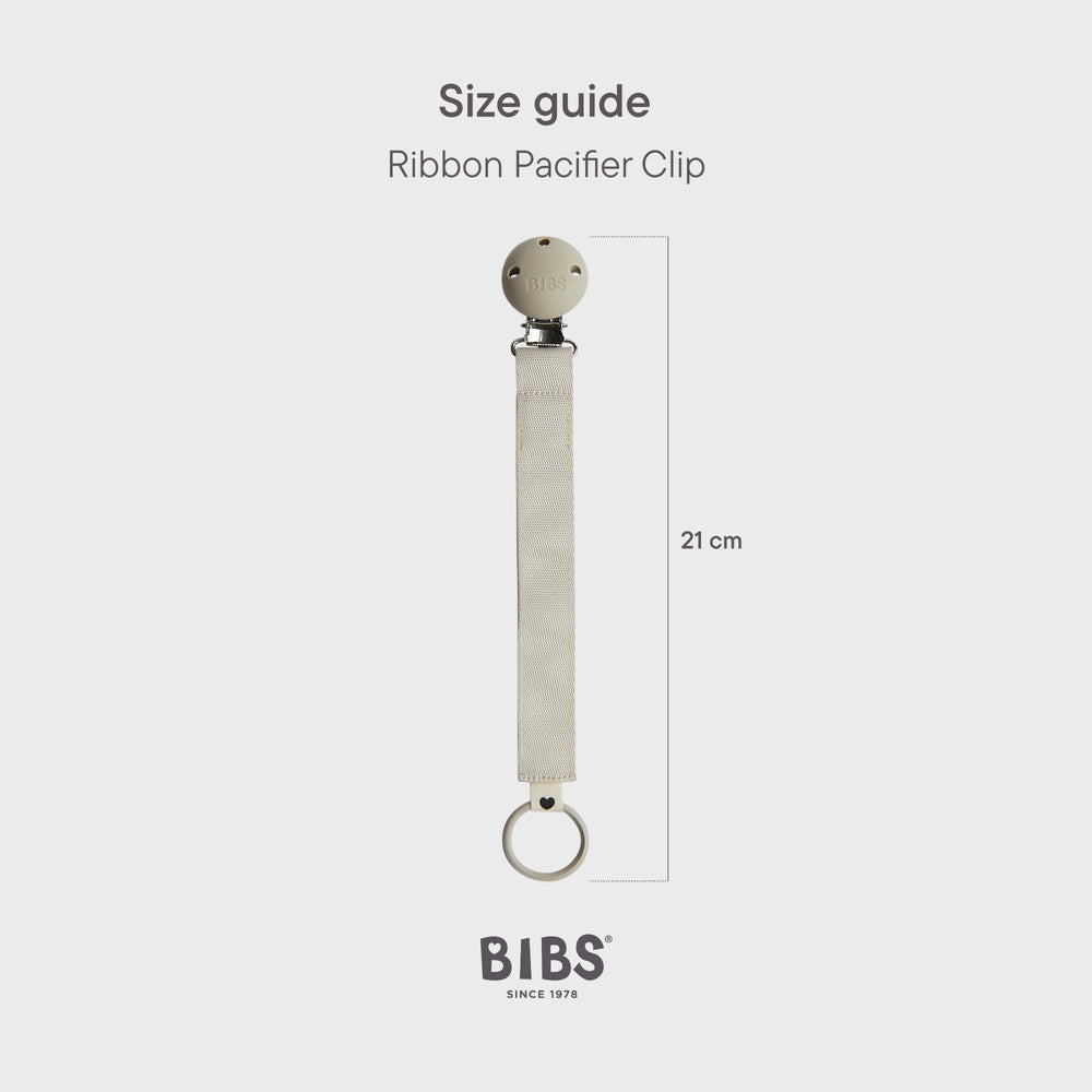 BIBS pacifier clip ribbon blush worn on a baby outfit demonstrates hands-free convenience