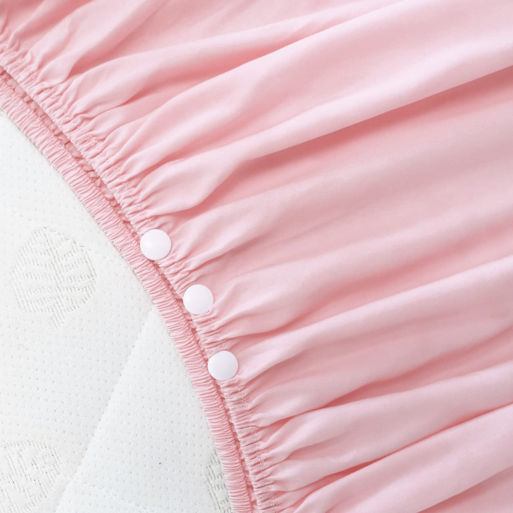 Biloban crib skirt close-up shows pleated pink dust-ruffle fabric detail.