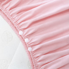 Biloban crib skirt close-up shows pleated pink dust-ruffle fabric detail.