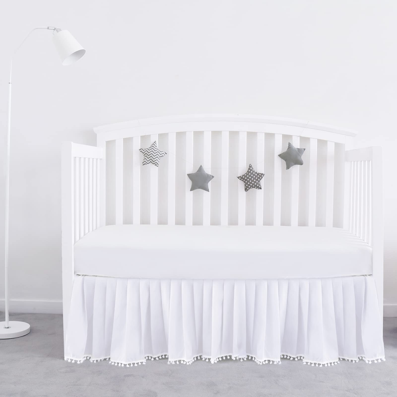 Biloban white crib skirt with pleated design and pompoms for a polished nursery