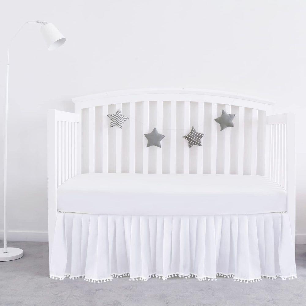 Biloban white crib skirt with pleated design and pompoms for a polished nursery