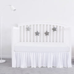 Biloban white crib skirt with pleated design and pompoms for a polished nursery