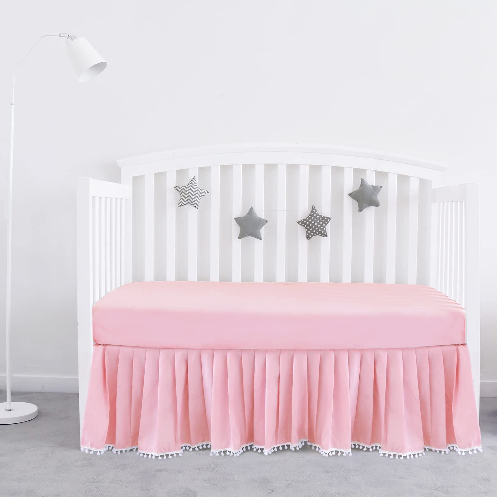 Biloban pink crib skirt pleated with pompoms enhances crib decor and tidy under-bed space
